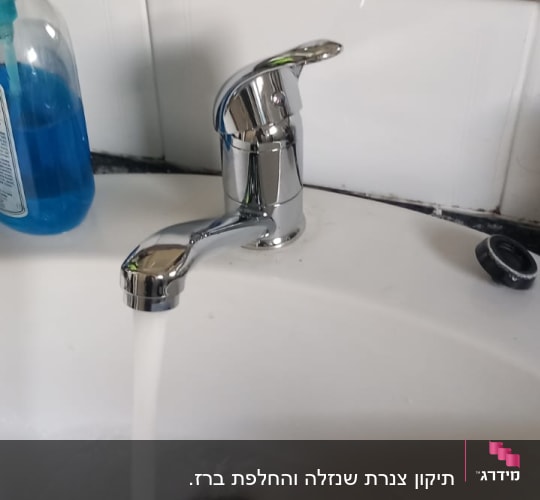 ברז מים זורמים בכיור עם ידית מתכת